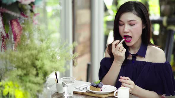 woman doing make-up with lipstick in a café