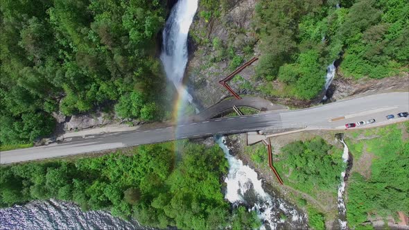 Massive Svandalsfossen waterfall creating rainbow on road bridge in Norway alt