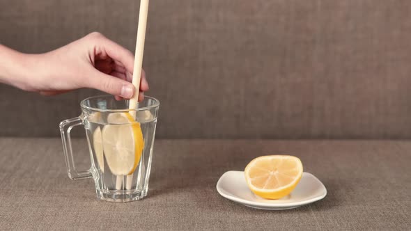A lemon drinking in a glass with straw.  alt