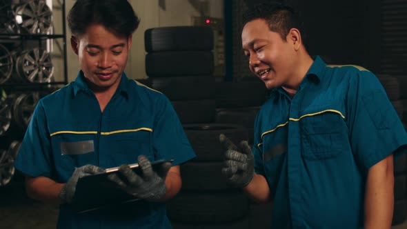 Two professional car mechanic using paperwork makes the oil and engine check to the car on lifted