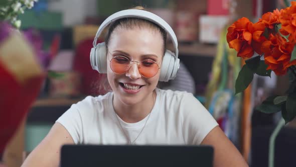 Florist Female in Headphones Communicates with Audience By Video Call Using a Laptop Girl Streamer alt