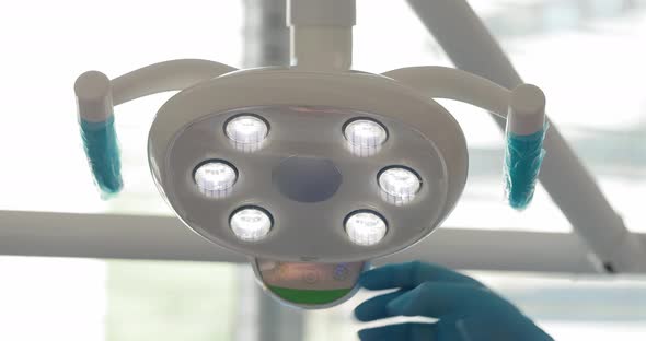 the Hand of a Dentist Doctor Turns on the Lamp of the Dental Chair in His Office Against the alt