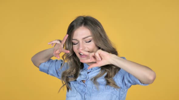 Pleased Smiling Young Girl Dancing Isolated on Yellow Background alt