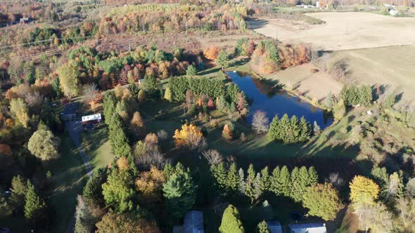 Aerial Drone Shot Flying Over Farm Pond with Fall Colors and Nearby Power Lines