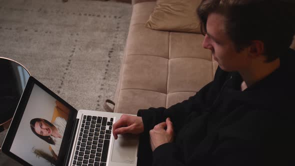 Closeup of Smiling Man Has Video Call Chatting on Laptop with Friend Sitting on Couch at Home alt