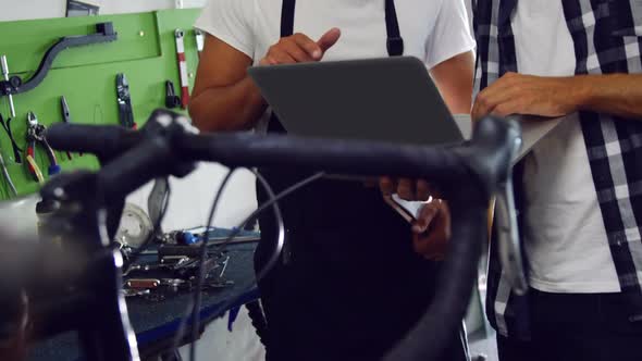 Mechanics discussing on laptop in workshop alt