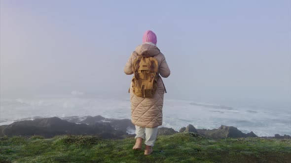 Slow Motion RED Camera Back View Woman with Backpack Looking at Ocean Waves 6K alt
