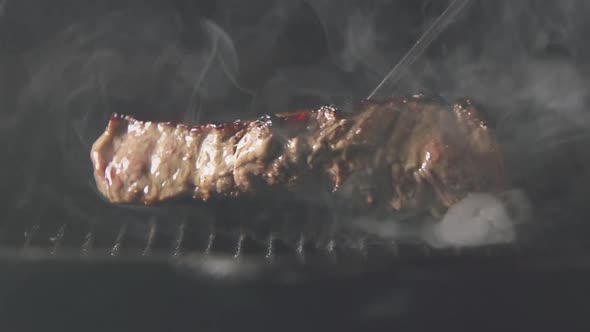 Cook Puts A Fried Steak Of Meat On A Grill
