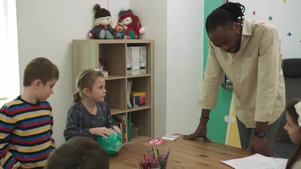 An African American Teacher Teaches a Group of People English at School alt