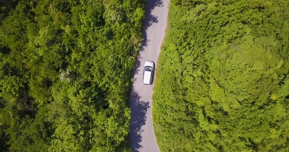 Aerial drone view of a minivan car vehicle driving on a rural road. alt