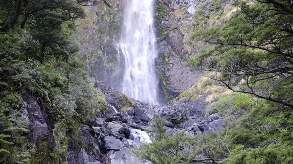 Panning up shot of Devil's Punchbowl Waterfall in Arthur's Pass, New Zealand alt