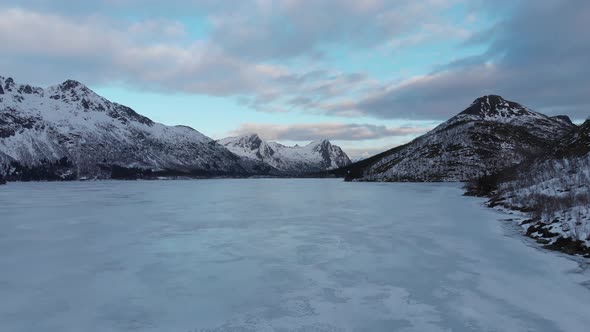 Frozen lake filmed from above with a drone, mountains in the background