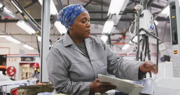 African American female car mechanic painting a body of a car alt