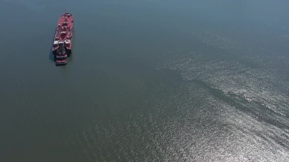 A drone view of a large red barge on the Hudson River in NY on a sunny day. The camera boom down and alt