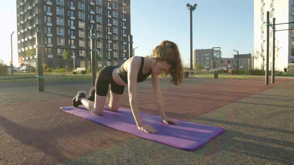 Slender Sexy Athletic Young Woman is Doing Warmup in Courtyard of Residential Complex on Gymnastic alt