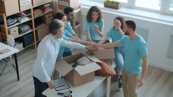Group of Volunteers in Uniform Joining Hands Expressing Teamwork in Charity Fund Office alt