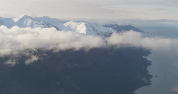 Aerial helicopter wide shot of fog bank and rivers cutting through dense Alaskan forest, drone foota alt