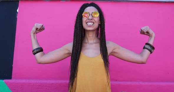 Young mixed race woman wearing trendy eyeglasses and showing muscle biceps alt