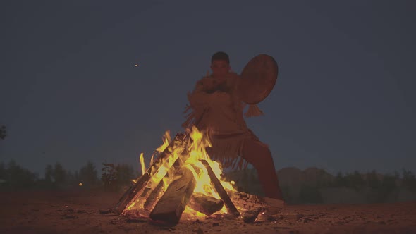 A Shaman with a Drum Jumps in Around the Fire in Clothes for the Ceremony alt