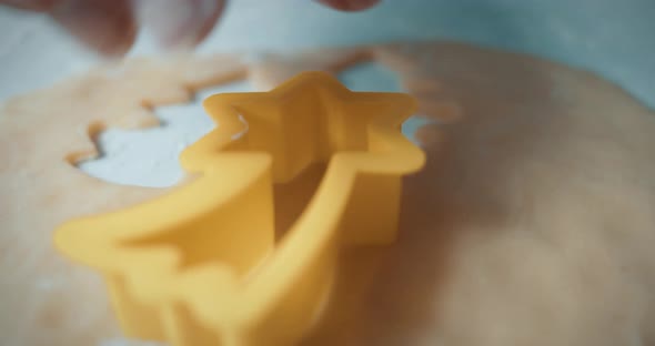 Woman's hand cuts the shape of a falling star from fresh, smooth cookie dough on baking sheet. Chris alt