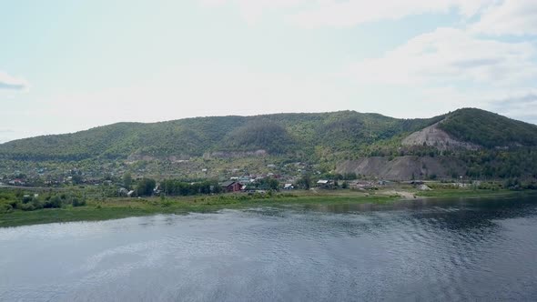 Calm Aerial View on Coast of River with Hills, Small Village