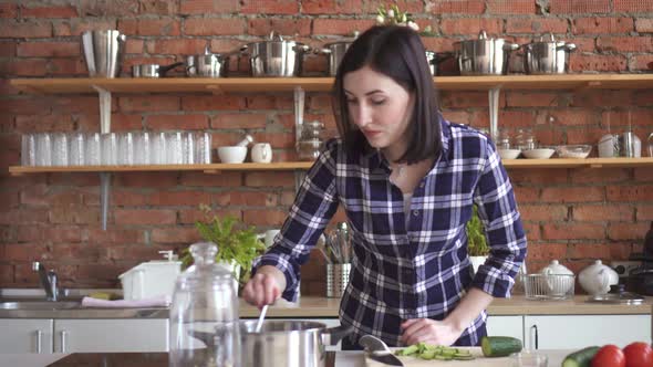 Woman Housewife in the Kitchen Trying Spoiled the Dish with a Spoon Out of the Pan alt