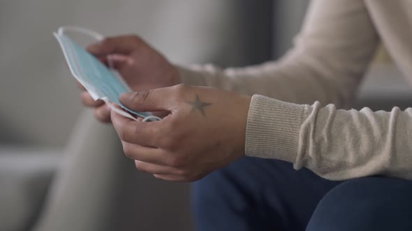 Closeup of Blue Coronavirus Face Mask in Male African American Hands alt