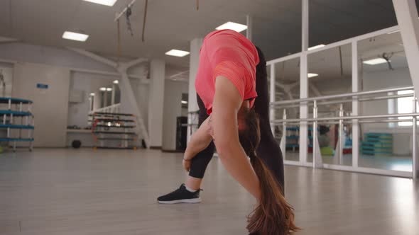A Beautiful Young Girl Stretches After Strength Exercises in the Gym and Makes Forward Bends with a alt
