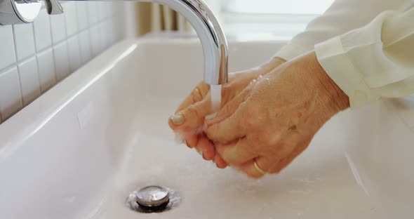 Senior woman washing her hands in sink 4k alt