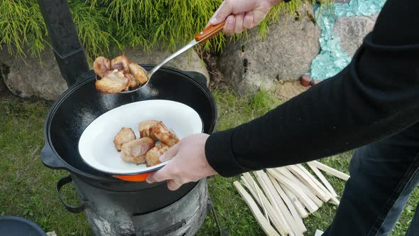A Man Takes Cooked Meat From Cauldron. Cooking Process, Frying Pork Meat