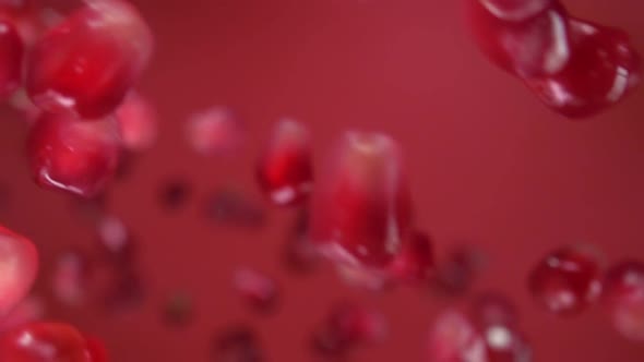Juicy Grains of Ripe Pomegranate Are Falling on the Wine Red Background alt