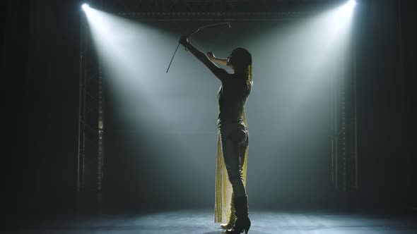 Silhouette of Dancing Greek Goddess Artemis with Bow and Arrow on Stage in a Dark Studio with Smoke alt