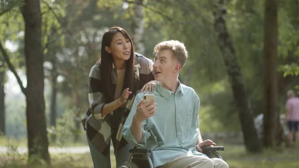 Being in the Public Park in a Good Weather a Young Sweet Couple Talk with Their Friends on the alt