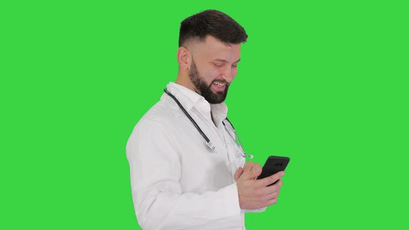 Arab Doctor Walking Using Smartphone and Laughing on a Green Screen, Chroma Key. alt