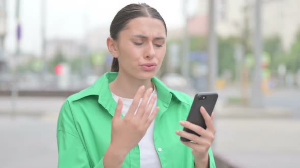 Upset Hispanic Woman Reacting to Loss on Smartphone Outdoor alt