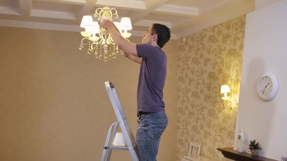 Man Changing a Burnt Out Light Bulb alt