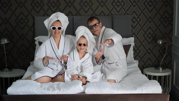 Family of Three in Bathrobes Having Fun in a Bed alt