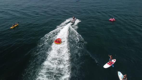 Happy People are Going to Swim on an Air Mattress Behind a Jet Ski alt