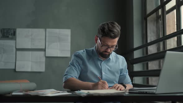 Engineer Works in a Bright Office Concentrates and Draws Blueprints alt
