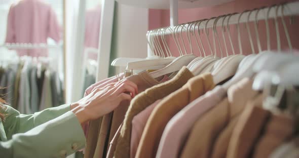Closeup of Female Hands Plucked Hanger Choosing Clothes in a Clothing Store alt