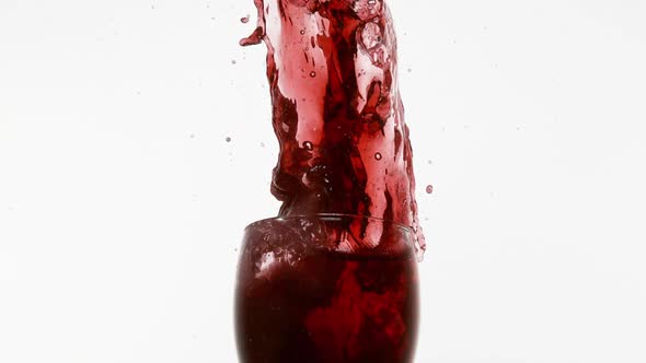 Glass Falling and Red Wine splashing against White Background, Slow Motion