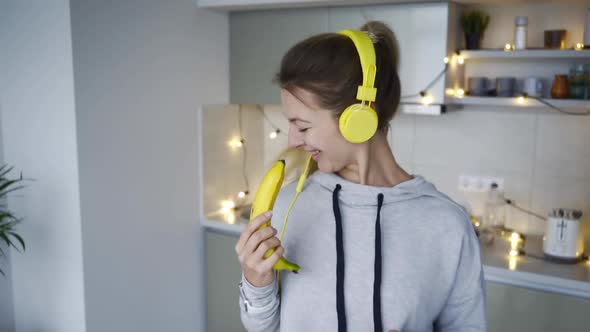 Joyful Lady with Headphones Dances Holding Banana