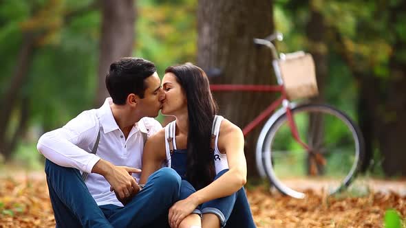 Teen couple with retro bike kissing in the park in autumn time