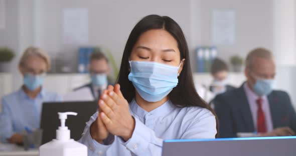 Asian Woman in Safety Mask Cleaning Hands with Antibacterial Gel at Office alt