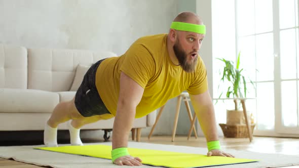 Fat Man in Yellow Sportswear Is Doing Sport Pushups Exercise on Mat at Home