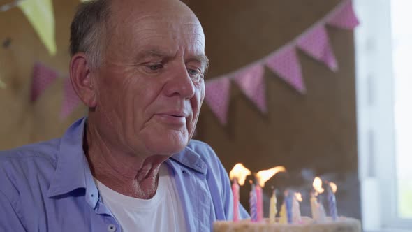 Old Handsome Man of Retirement Age Has Fun at Birthday Party and Enjoys Blowing Out Candles on alt