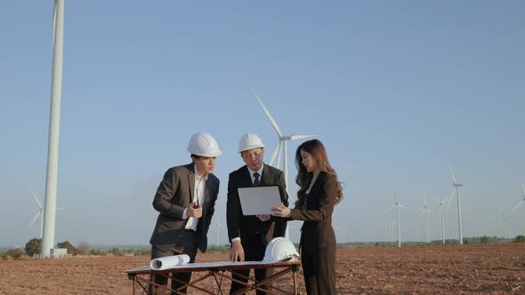 inspector and an engineer with a secretary are inspecting a project in a wind turbine field