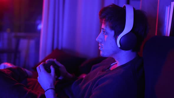 a Concentrated Man Playing Video Games Smiling with Headphones Looking at the Tv