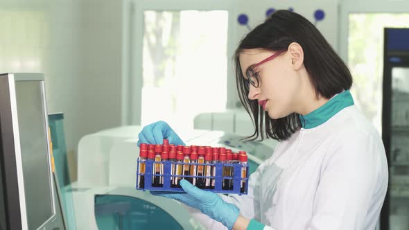 Young Female Scientist Examining Test Tubes with Blood Samples alt