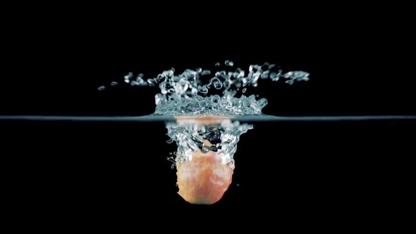 An Apple Falls Into The Water On A Black Background